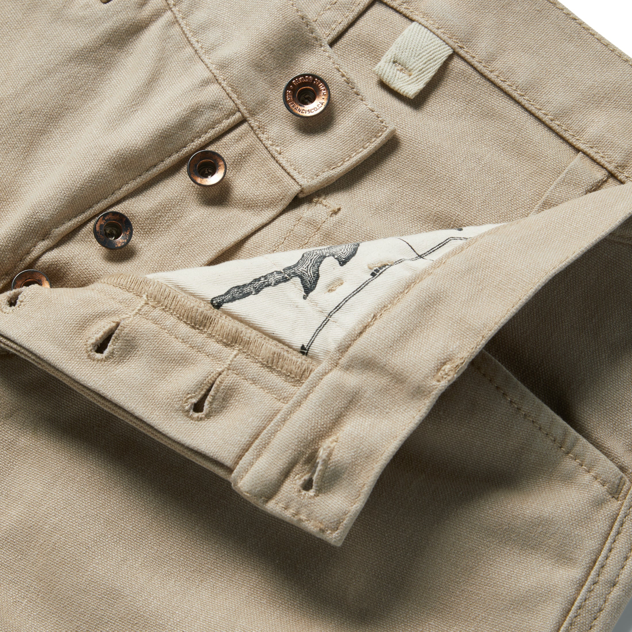 material shot of the buttons and map pocket printing on The Chore Pant in Sand Boss Duck, Bottoms by Taylor Stitch