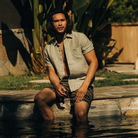 fit model sitting by a pool in The Short Sleeve California in Army Hemp
