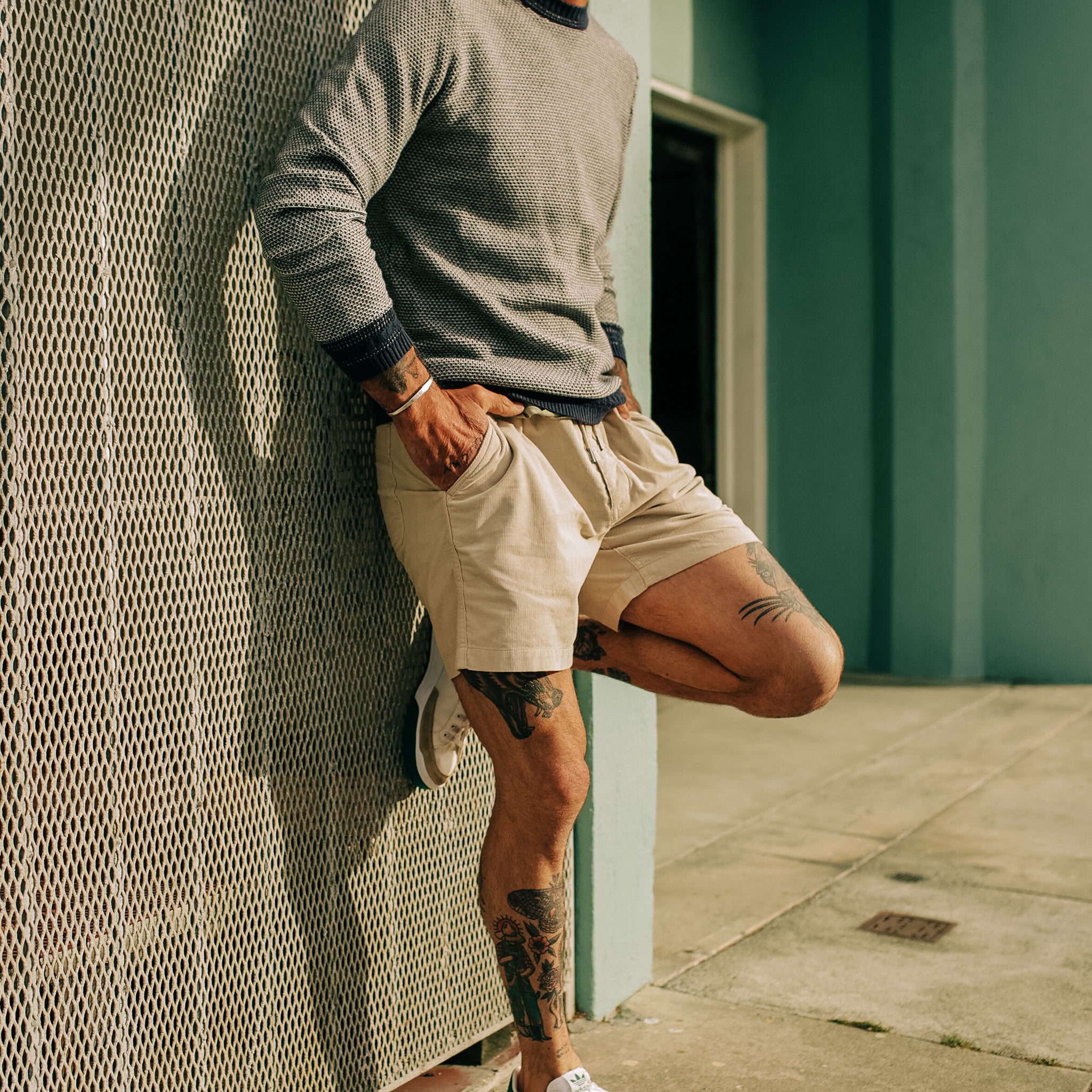 model leaning against a wall wearing The Après Short in Natural Pinwale, Shorts by Taylor Stitch