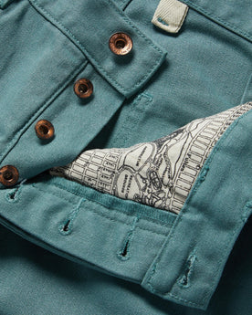 material shot of the buttons and map pocket printing on The Chore Pant in Ocean Boss Duck, Bottoms by Taylor Stitch