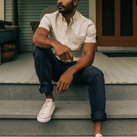 fit model sitting on a porch in The Democratic Foundation Pant in Organic Dark Navy