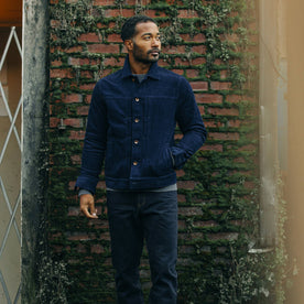 fit model wearing The Dispatch Jacket in Indigo Cord in front of a brick wall