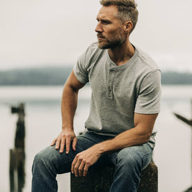 fit model sitting by the pier wearing The Short Sleeve Heavy Bag Henley in Aluminum