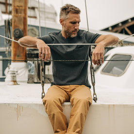 fit model wearing The Heavy Bag Tee in Dark Slate while sitting on the edge of a boat