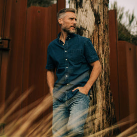 fit model wearing The Short Sleeve Jack in Indigo Seersucker while leaning on a tree trunk