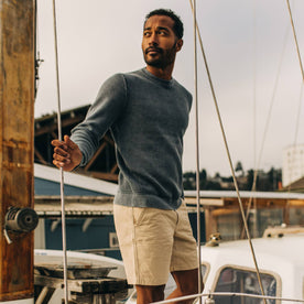 fit model looking over right shoulder wearing The Moor Sweater in Washed Indigo on a boat