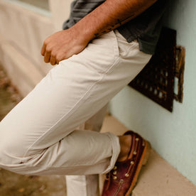 fit model leaning against wall in The Morse Pant in Sand Slub