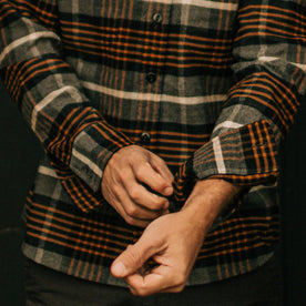 fit model rolling up sleeves of The Moto Shirt in Orange Plaid