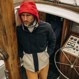 fit model wearing The Navigator Jacket in Natural and Navy Colorblock while standing on a yacht
