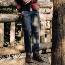 fit model leaning against a fence wearing The Democratic Brushed Back Jean in Sawyer Wash Organic Selvage
