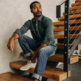 fit model sitting on stairs wearing The Utility Shirt in Dark Slate Heavy Bag