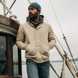 fit model standing on a boat with his hands in the pockets of The Workhorse Hoodie in Sand Boss Duck