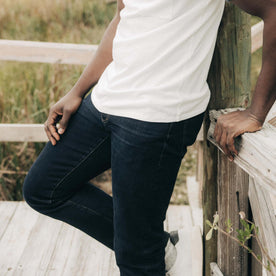 fit model leaning against the wall wearing The Demcratic Jean in Wallace Wash Organic Selvage