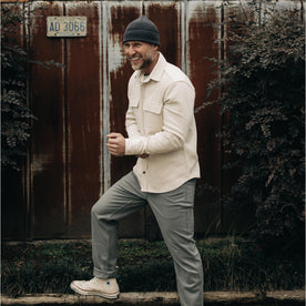 fit model stepping on a log in The Ledge Shirt in Natural Twill