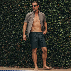 fit model wearing The Adventure Short in Navy from Taylor Stitch, standing by pool, shirt unbuttoned