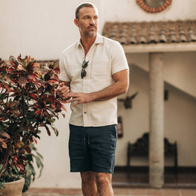 fit model wearing The Apres Short in Navy Hemp, next to plant outside