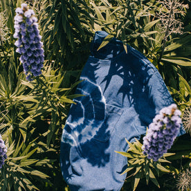 outdoor material shot of The Botanical Dye Tee in Indigo, in bed of plants