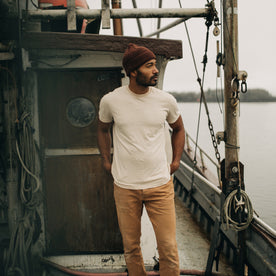 fit model standing on an old boat in The Cotton Hemp Tee in Sand