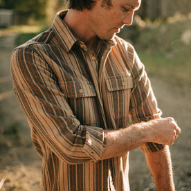 fit model rolling up the sleeves on The Ledge Shirt in Sunset Stripe