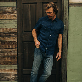 fit model standing against a doorframe in The Short Sleeve Western in Indigo Linen