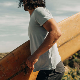 fit model holding surfboard in The Cotton Hemp Tee in Ocean