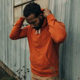 fit model putting up the hood on The Fillmore Hoodie in Rust
