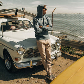fit model leaning against a vintage car in The Fillmore Hoodie in Ocean and Natural 