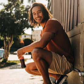 fit model sitting in The Heavy Bag Tee in Dusty Rose Embroidered Stripe