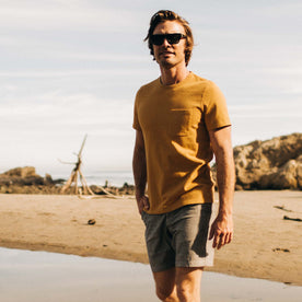 fit model wearing The Heavy Bag Tee in Gold by the beach