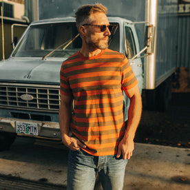 fit model wearing The Organic Cotton Tee in Rust Stripe in front of a blue truck