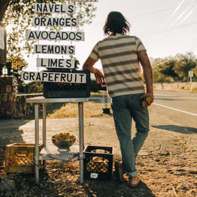fit model posing at a fruit stand facing the back, in The Organic Cotton Tee in Seagrass Stripe