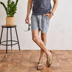 fit model holding a pair of sunglasses with his legs crossed in The Apres Short in Tradewinds Micro Cord