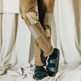 material shot of The Atelier and Repairs Chino in British Khaki, legs crossed on model