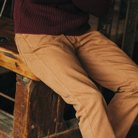 fit model wearing The Camp Pant in Tobacco Boss Duck, sitting on bench, Bottoms by Taylor Stitch