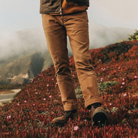 fit model wearing The Chore Pant in Tobacco Boss Duck, on side of road