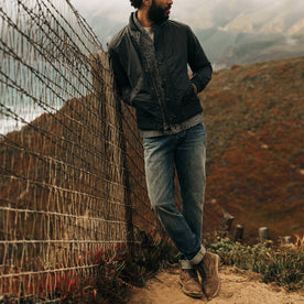 fit model wearing The Democratic Jean in in 18 Month Wash Organic Selvage, leaning against fence