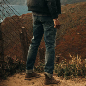 fit model wearing The Democratic Jean in in 18 Month Wash Organic Selvage, standing in dirt