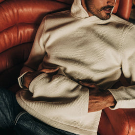 fit model wearing The Nomad Hoodie in Natural Twill hands in pocket, reclining
