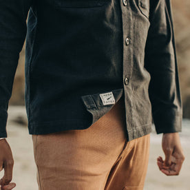 fit model wearing The Shop Shirt in Coal Boss Duck, logo showing, up close