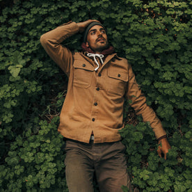 fit model wearing The Shop Shirt in Tobacco Boss Duck, laying in clovers