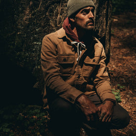 fit model wearing The Shop Shirt in Tobacco Boss Duck, sitting against tree