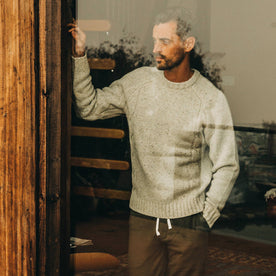 fit model wearing The Topside Sweater in Natural Cable Knit, looking through window