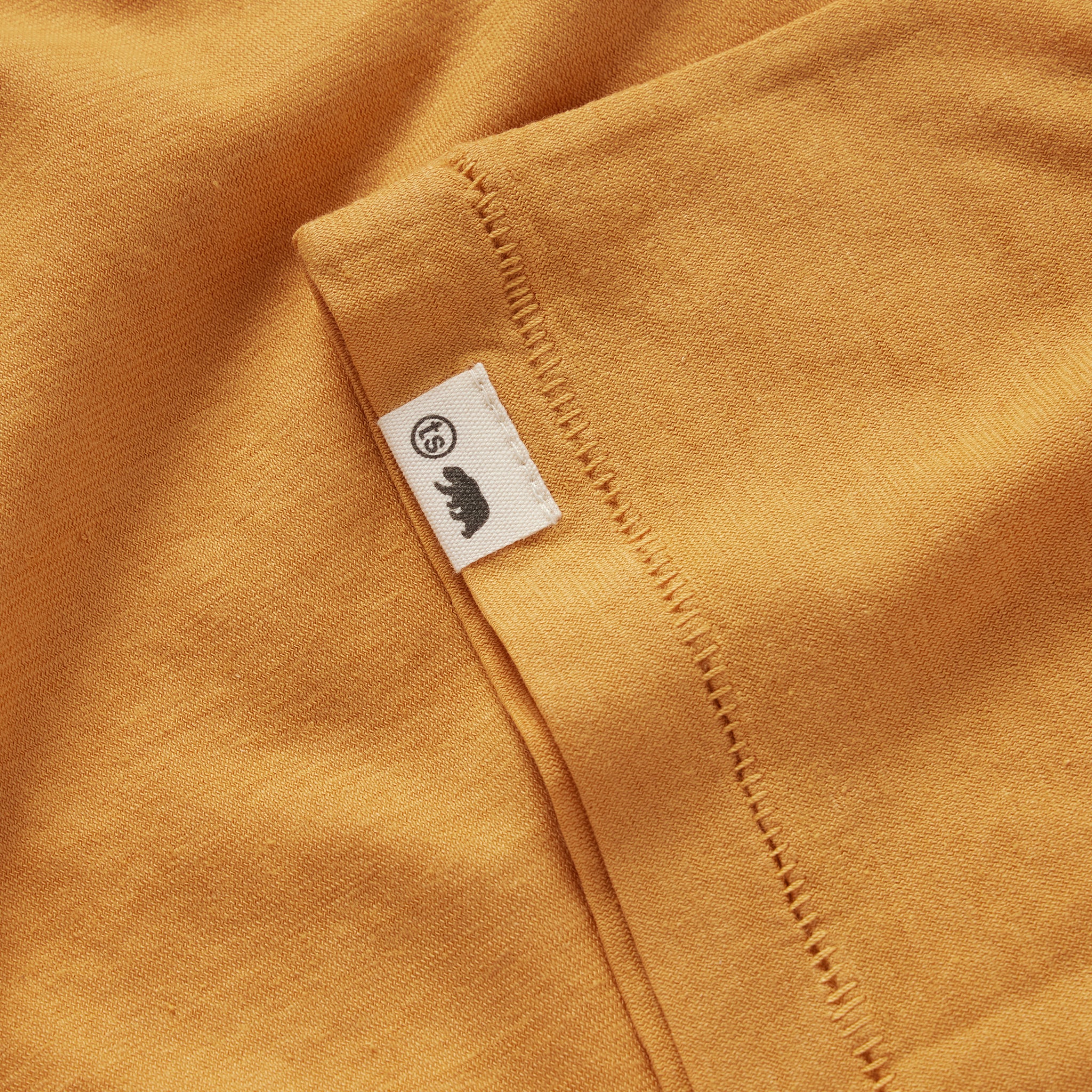 material shot of the TS tag on the sleeve of The Cotton Hemp Tee in Mustard, Knits by Taylor Stitch