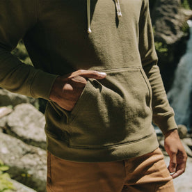 fit model with his hand in the kangaroo pocket of The Fillmore Hoodie in Cypress Terry
