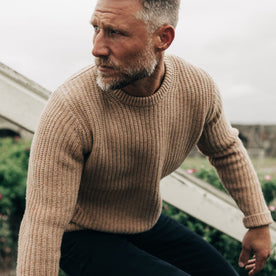 fit model sitting wearing The Fisherman Sweater in Camel