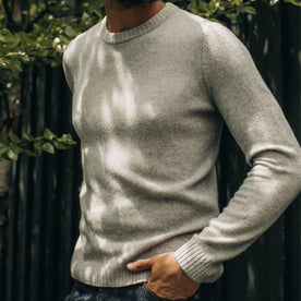 fit model with his hand in his pocket wearing The Lodge Sweater in Heather Grey