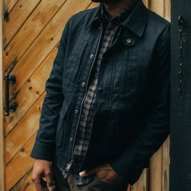 fit model leaning against the wall wearing The Pathfinder Jacket in Navy Dry Wax