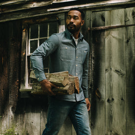 fit model carrying logs wearing The Utility Shirt in Rinsed Selvage Chambray