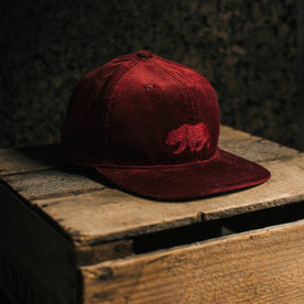 fit model put The Ball Cap in Burgundy Cord on an apple box