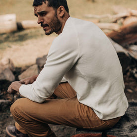 fit model sitting on a log stump in The Heavy Bag Waffle Henley in Natural